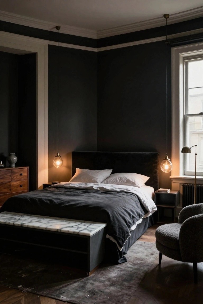 Corner view of a master bedroom with dark charcoal walls, black velvet upholstered king bed with gray duvet and white pillows, two brass globe pendant lights, wooden dresser, marble-top bench at bed foot, small side table, adjustable lamp, and gray upholstered armchair on hardwood floor with dark rug.