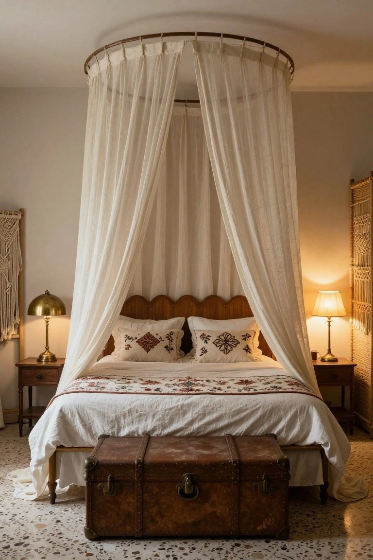 Bedroom with a bed under a circular white sheer canopy frame, wooden headboard, white bedding with embroidered pillows, brass dome lamps on wooden nightstands, macrame wall hangings, bamboo screens, and a brown leather trunk at the foot on a terrazzo tile floor.