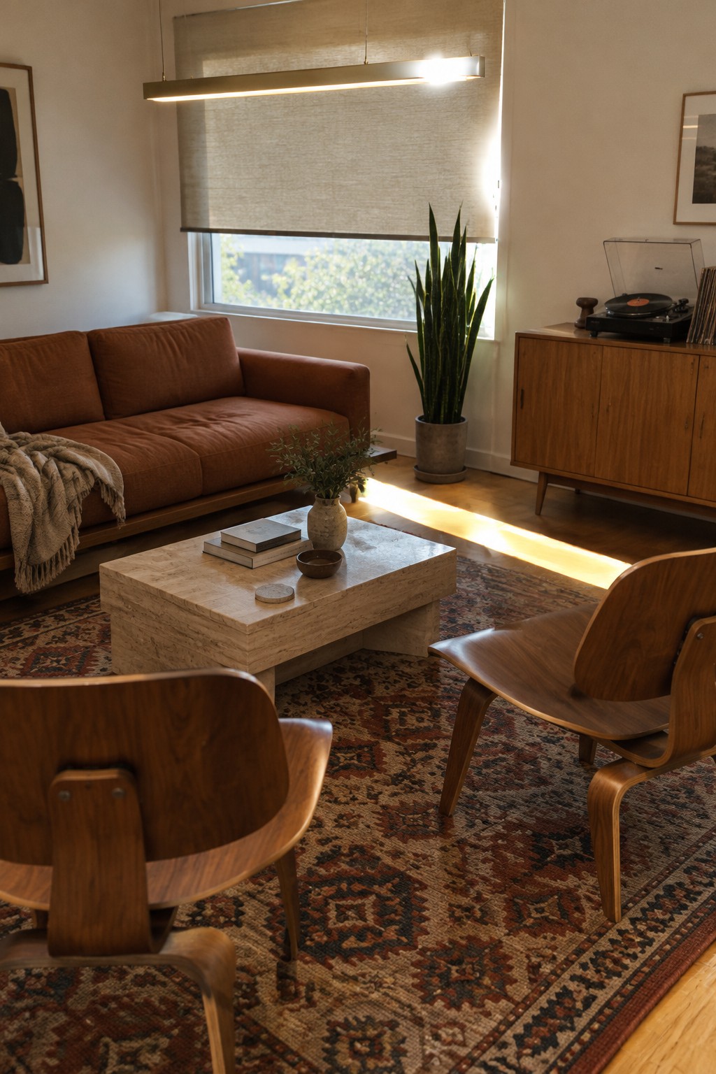 A low rust-colored sofa and two wooden lounge chairs sit around a stone coffee table in a living room.